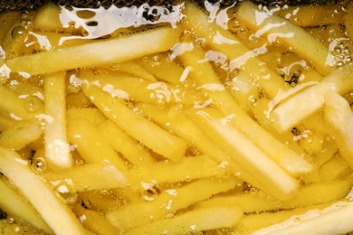 Photo of Cooking delicious french fries in hot oil, closeup