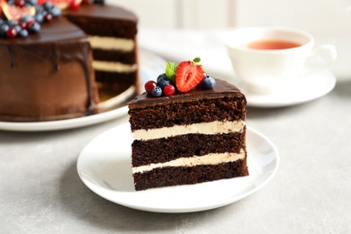 Photo of Plate with slice of chocolate sponge berry cake on grey table