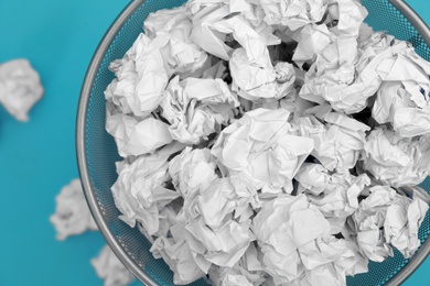 Photo of Metal bin with crumpled paper on color background, top view