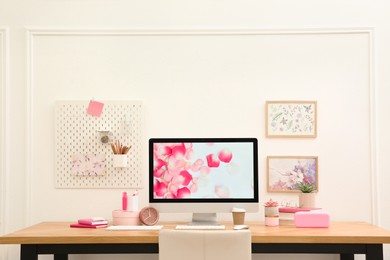 Photo of Stylish workplace with computer on wooden desk near white wall. Interior design