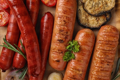 Flat lay composition with delicious grilled sausages on table, closeup. Barbecue food