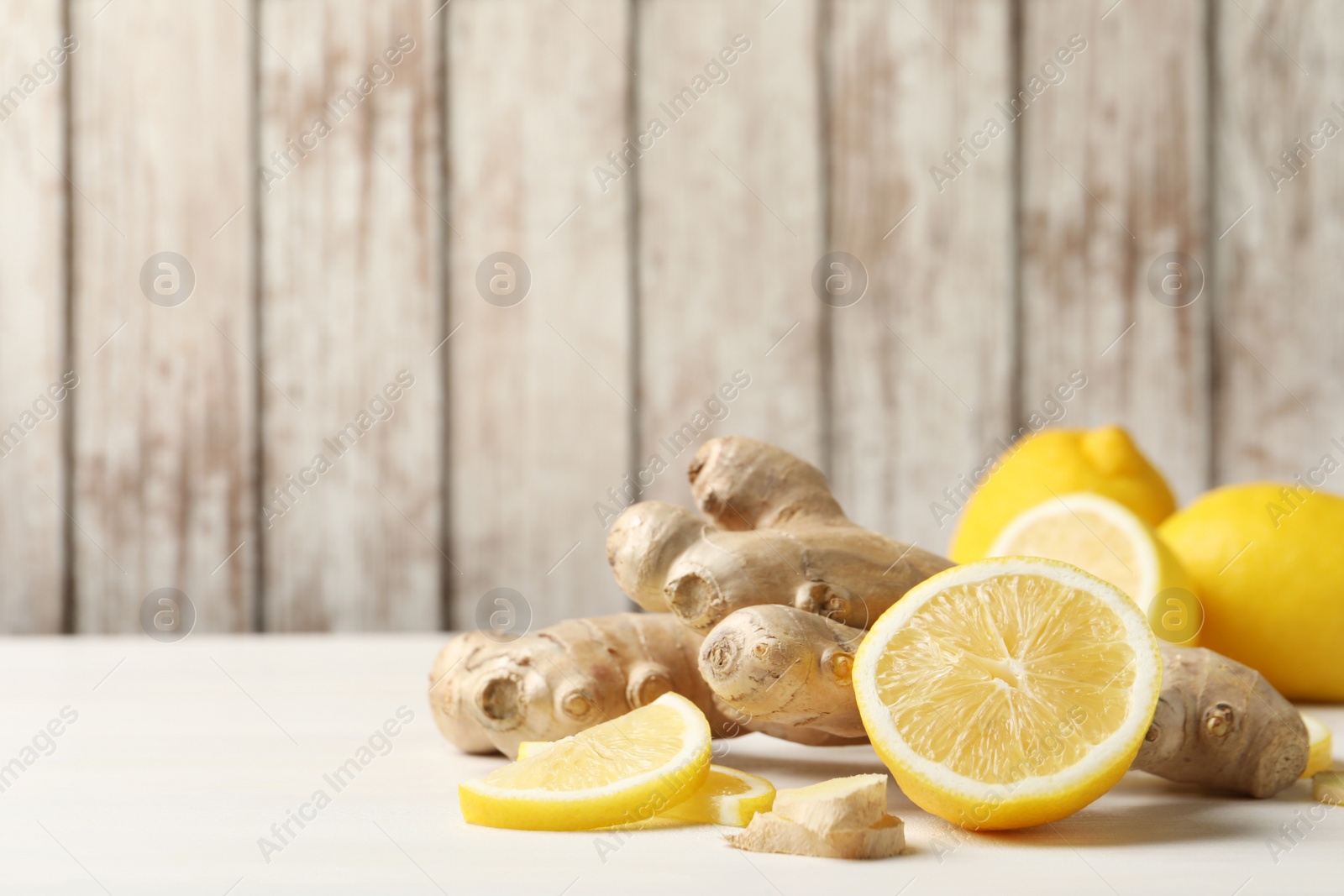 Photo of Fresh lemons and ginger on white table. Space for text