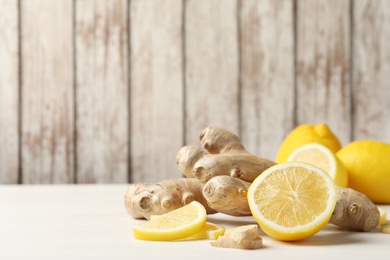 Photo of Fresh lemons and ginger on white table. Space for text