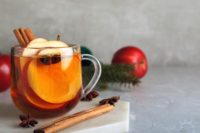 Photo of Aromatic hot mulled cider on light grey marble table. Space for text