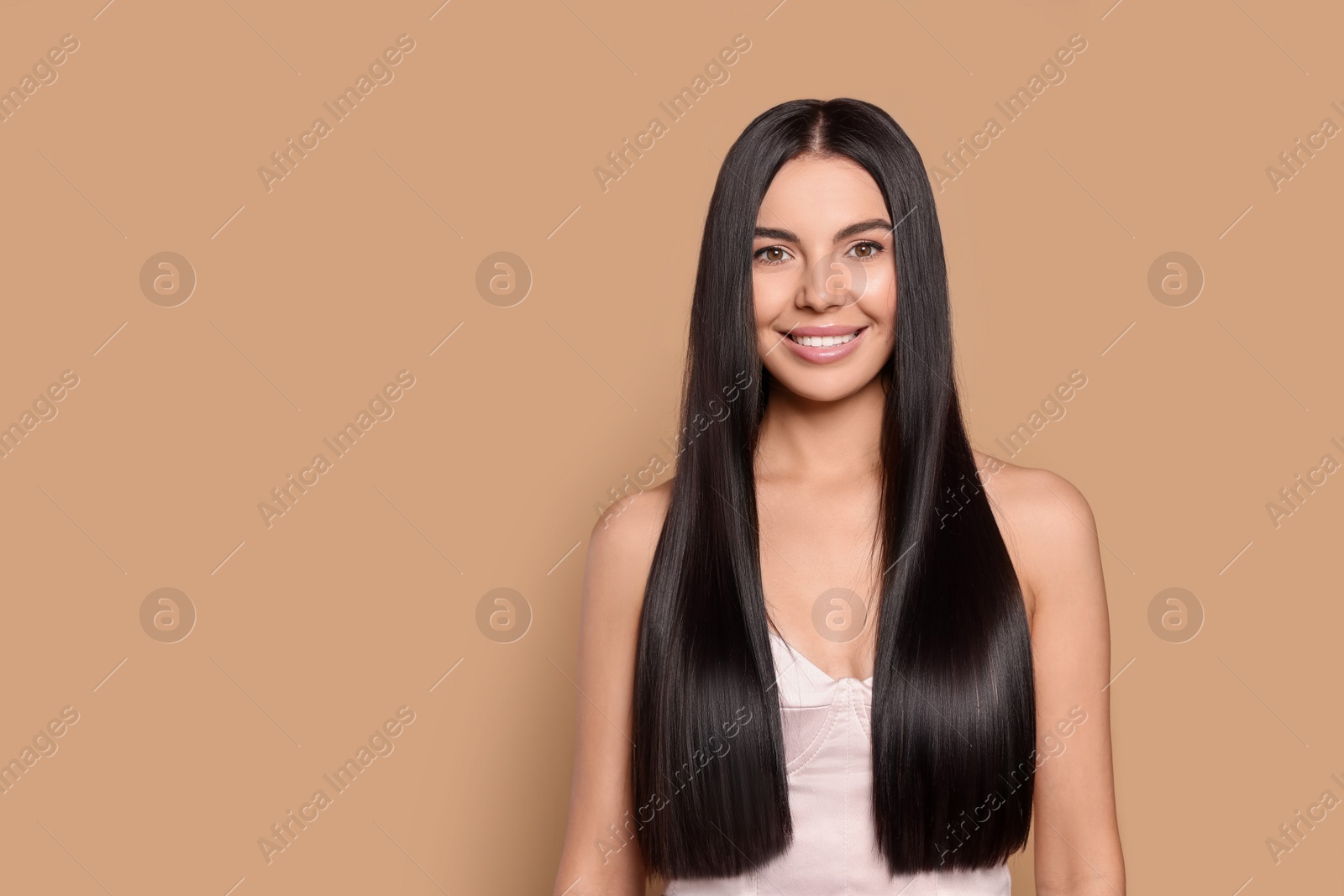 Photo of Portrait of beautiful young woman with healthy strong hair on beige background, space for text