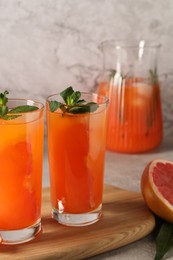 Photo of Tasty freshly made grapefruit juice with mint on table