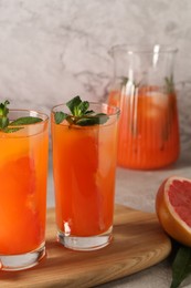 Tasty freshly made grapefruit juice with mint on table