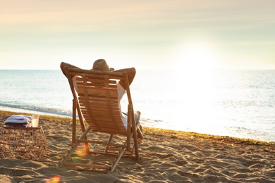 Photo of Man relaxing on deck chair at sandy beach. Summer vacation