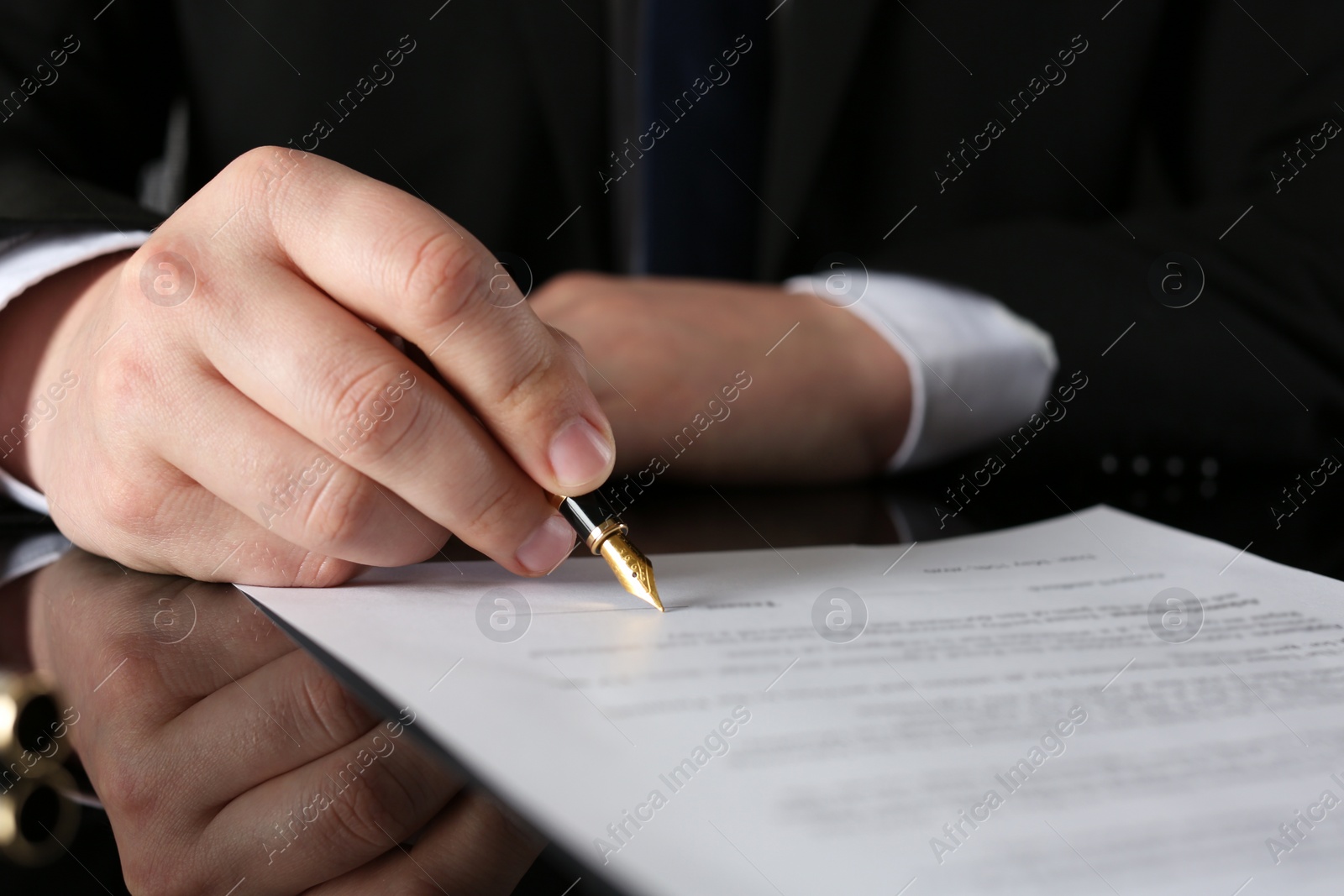 Photo of Notary signing document at black table, closeup