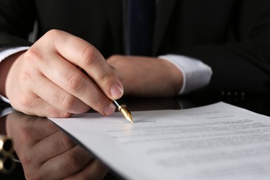 Notary signing document at black table, closeup