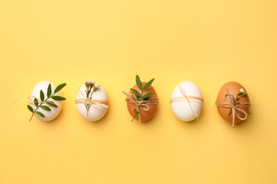 Photo of Festively decorated chicken eggs on yellow background, flat lay. Happy Easter