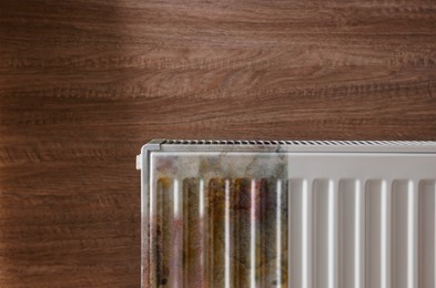 Image of Modern panel radiator affected by rust on wooden background