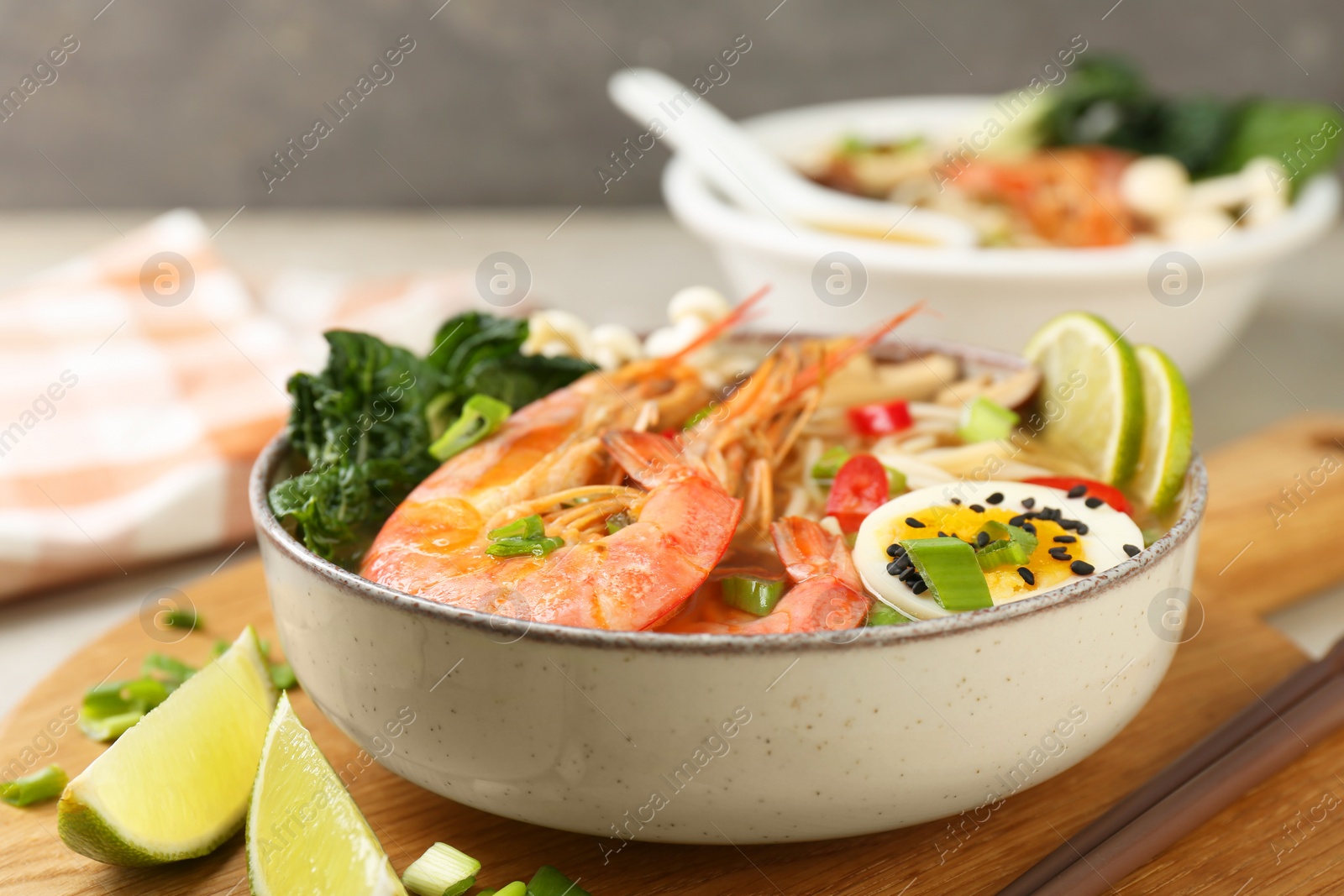 Photo of Delicious ramen with shrimps and egg in bowl on table, closeup. Noodle soup