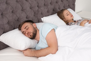 Young couple sleeping together in bed at home