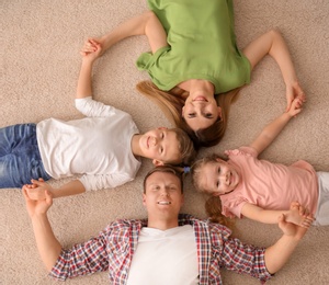 Photo of Happy family lying on cozy carpet at home, top view