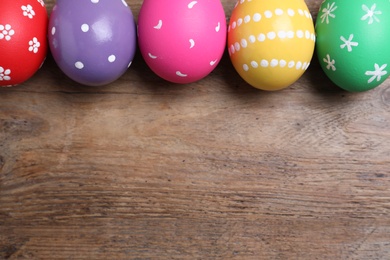 Photo of Colorful eggs on wooden background, flat lay with space for text. Happy Easter