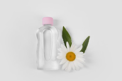 Photo of Transparent bottle with baby oil and flower on white background, flat lay