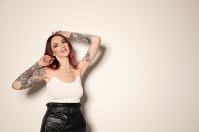 Photo of Beautiful woman with tattoos on arms against light background. Space for text
