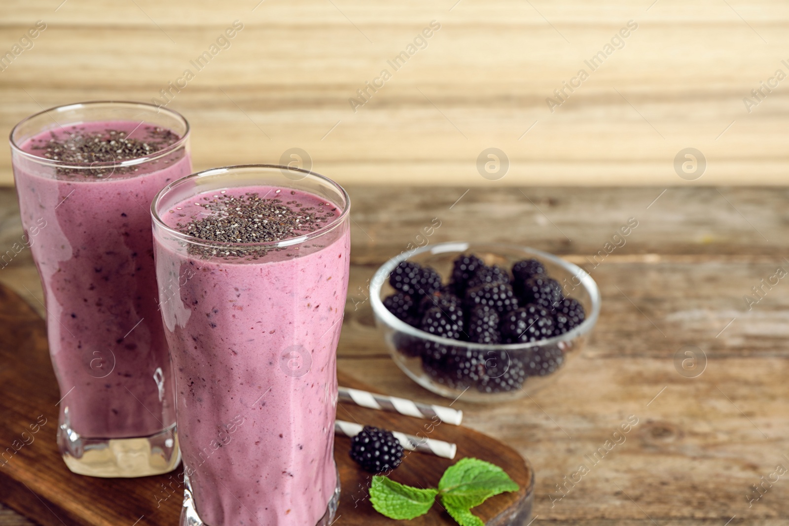 Photo of Delicious blackberry smoothie in glasses on wooden table. Space for text