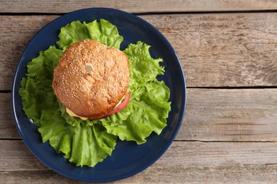 Photo of Delicious vegetarian burger on wooden table, top view. Space for text