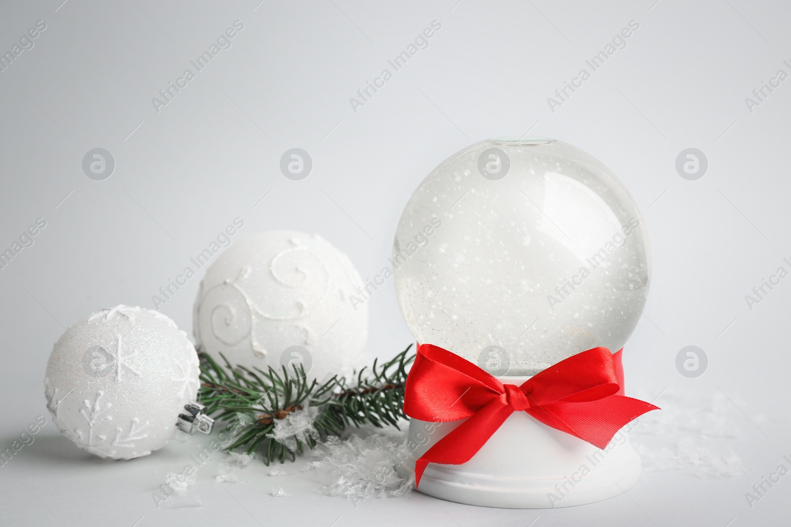 Photo of Beautiful empty snow globe, Christmas balls and fir branches on light grey background