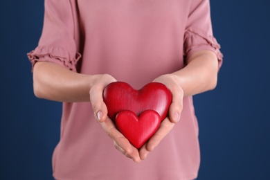Photo of Woman holding decorative hearts on color background, closeup