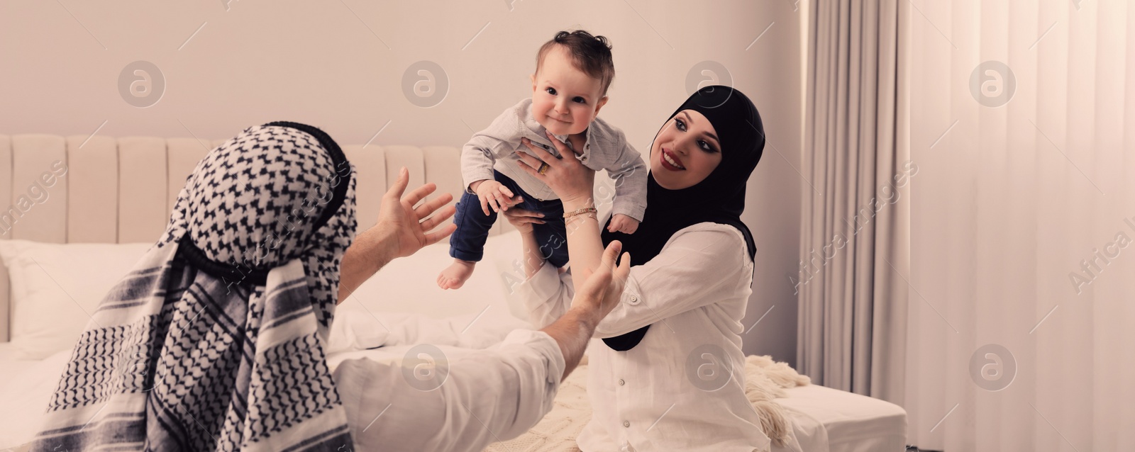 Image of Happy Muslim family with little son in bedroom. Banner design 