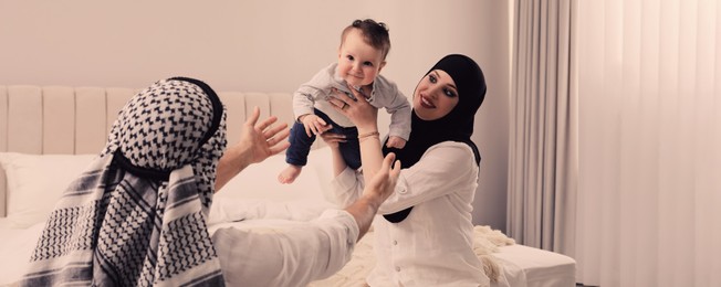 Happy Muslim family with little son in bedroom. Banner design 