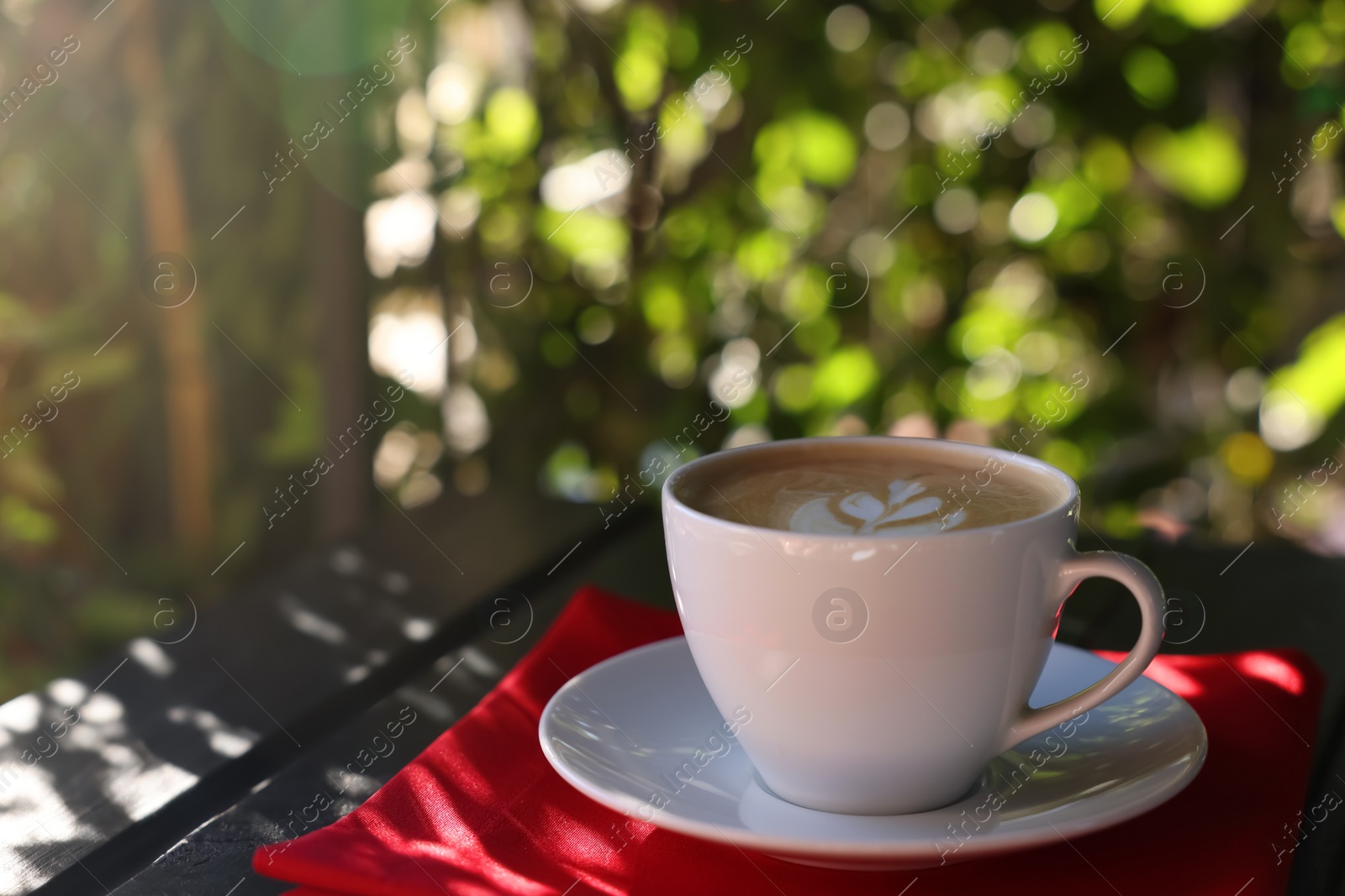 Photo of Cup of aromatic coffee with foam on table in outdoor cafe. Space for text