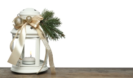 Photo of Decorated Christmas lantern with burning candle on wooden table, space for text