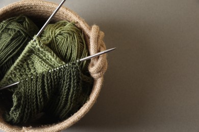 Green knitting, needles and soft yarns on light background, top view. Space for text