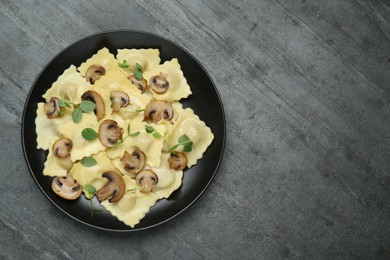 Photo of Delicious ravioli with mushrooms on grey table, top view. Space for text