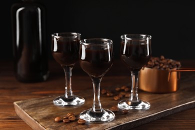 Shot glasses with coffee liqueur and beans on wooden table