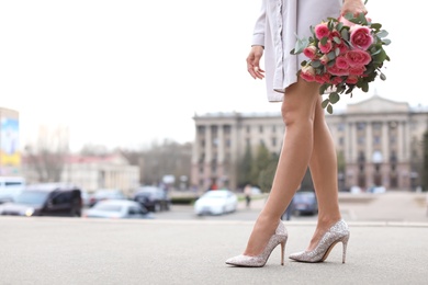 Young woman in elegant shoes walking on street