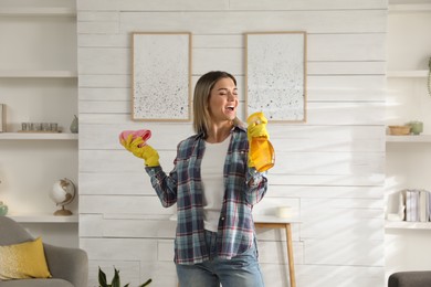 Photo of Woman with spray bottle and rag singing while cleaning at home