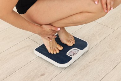 Photo of Woman standing on floor scales indoors, closeup