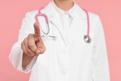 Photo of Doctor with stethoscope pointing on pink background, closeup