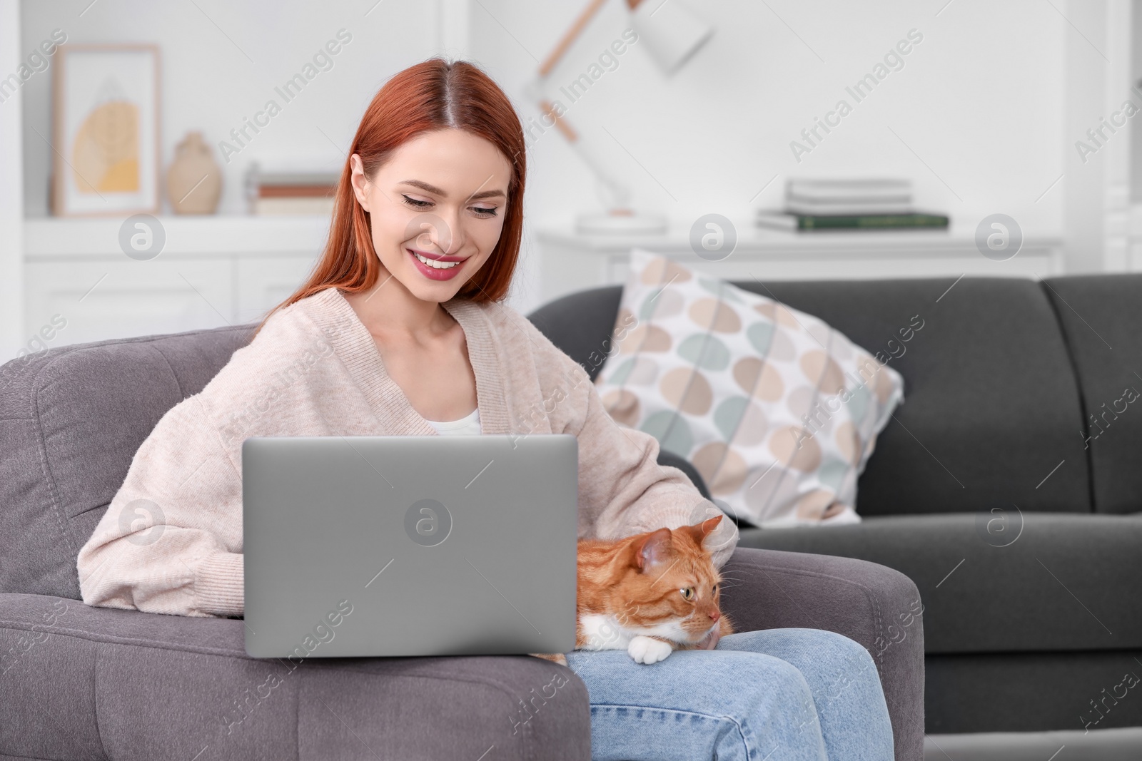 Photo of Happy woman with cat working in armchair at home