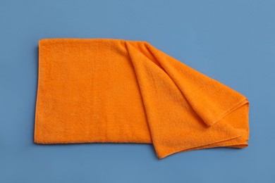 Photo of Folded orange beach towel on blue background, top view