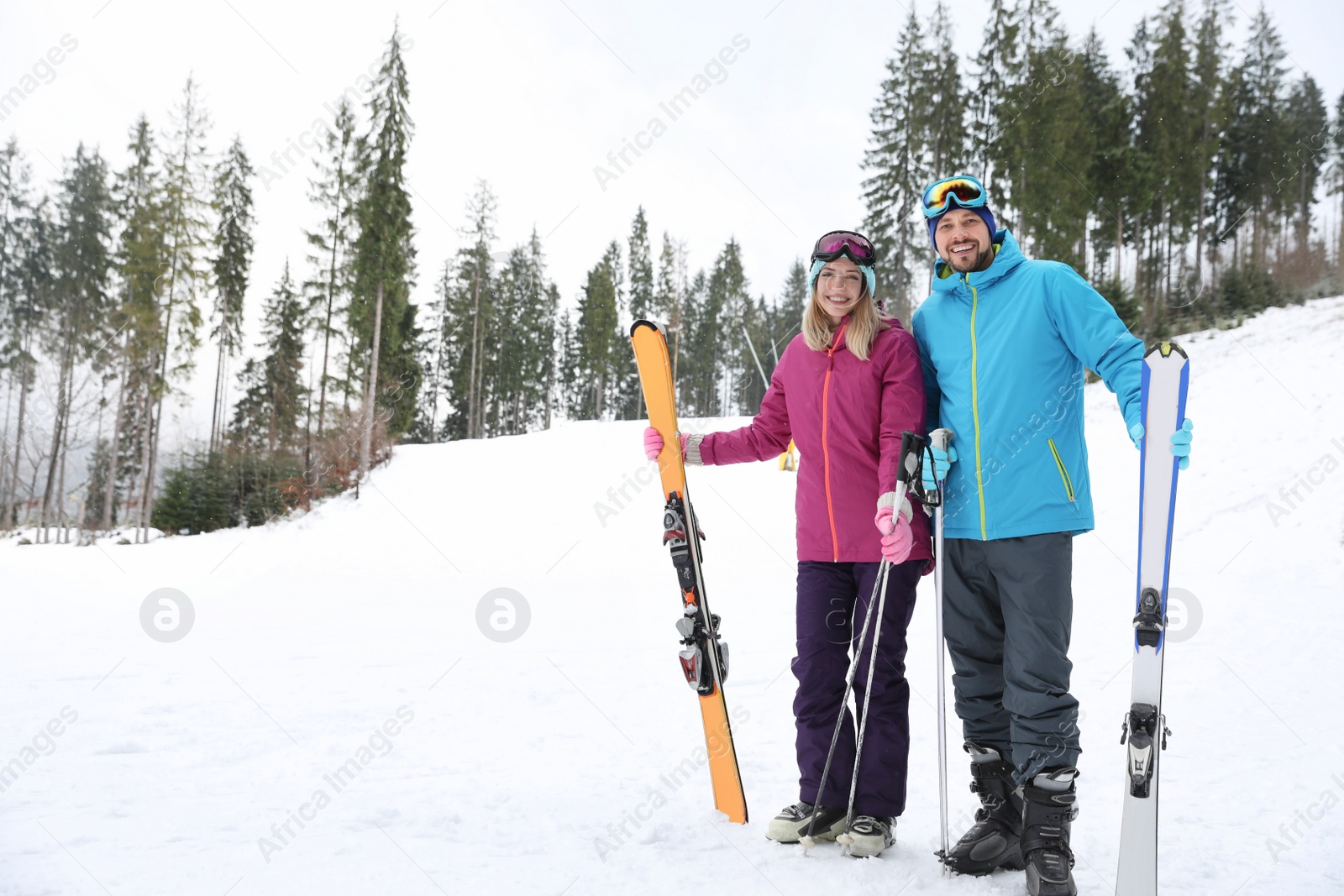 Photo of Couple of skiers on slope at resort, space for text. Winter vacation