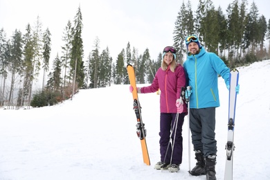 Photo of Couple of skiers on slope at resort, space for text. Winter vacation