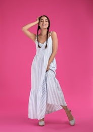 Young woman wearing stylish dress on pink background