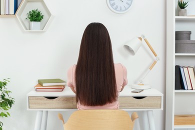 Photo of Home workplace. Woman working at comfortable desk in room, back view