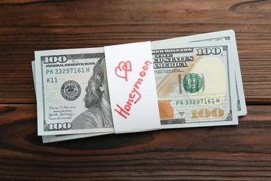 Stack of money with word Honeymoon on wooden table, top view