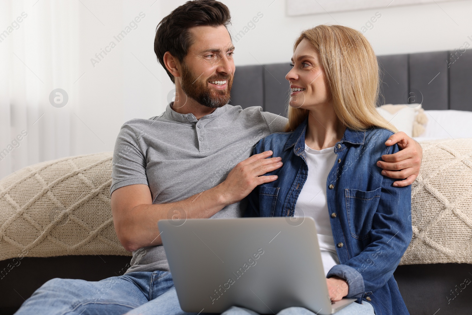 Photo of Happy couple spending time together and using laptop at home