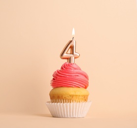 Birthday cupcake with number four candle on beige background