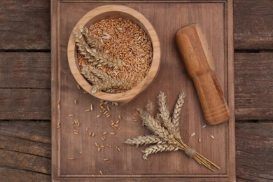 Photo of Mortar, pestle and ears of wheat on wooden table, flat lay
