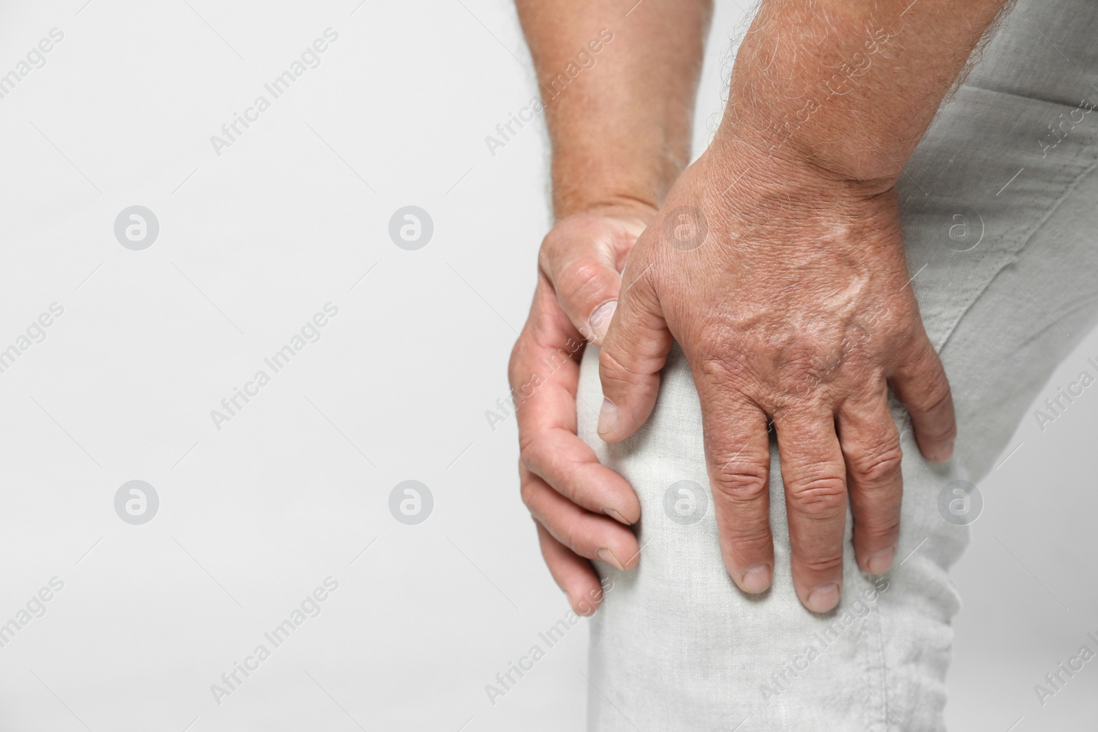 Photo of Senior man having knee problems on grey background, closeup. Space for text