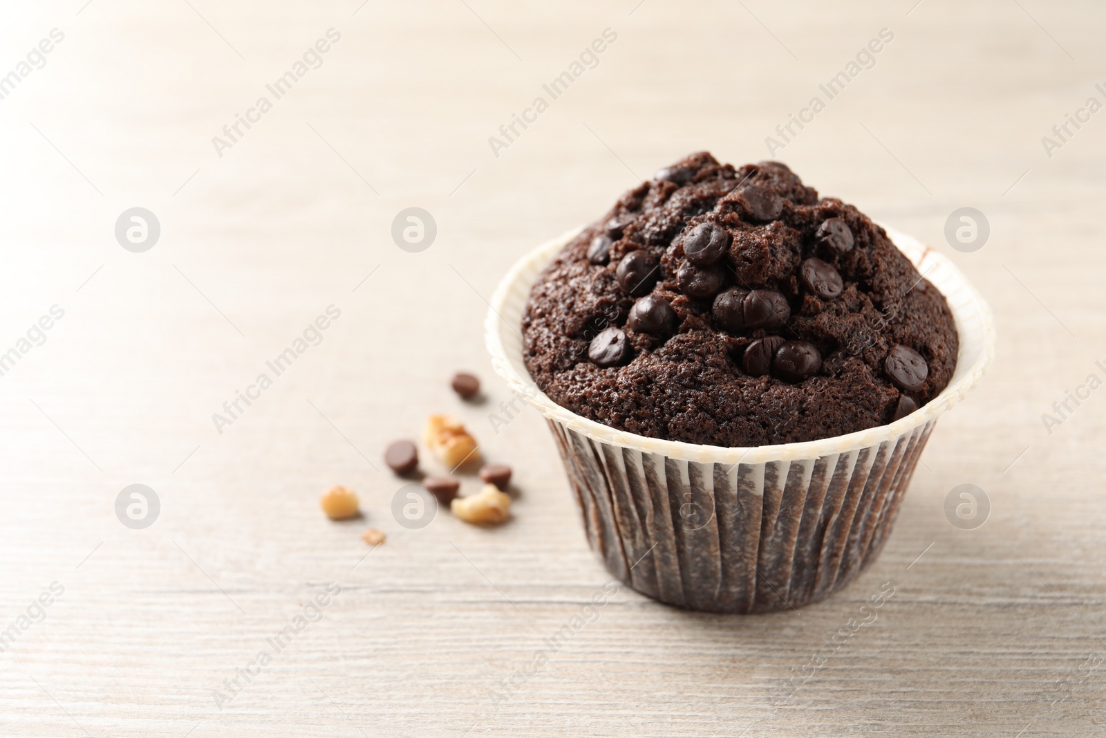 Photo of Delicious chocolate muffin on white wooden table, closeup and space for text