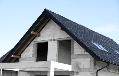 Photo of Unfinished house with black roof against blue sky